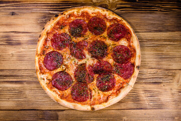 Pizza with salami sausage and parmesan cheese on a wooden table. Top view
