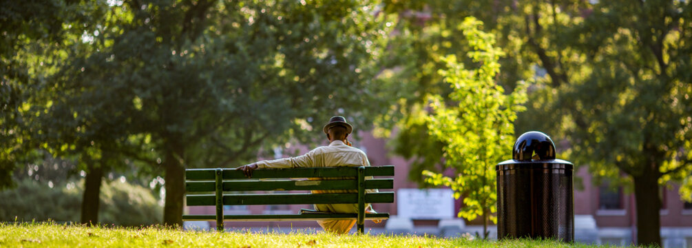 Man in a hat sitting on a park bench  alone