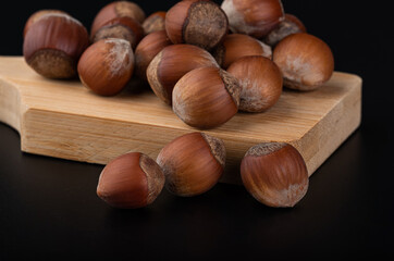 Beautiful young hazelnuts on a wooden board close-up and blurred background on a glossy black background