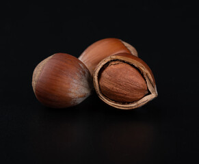 Whole and split hazelnuts close-up on glossy black background
