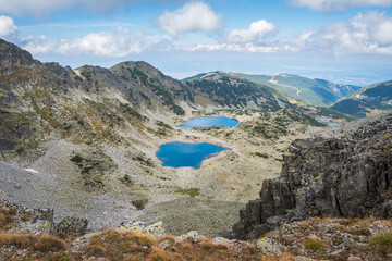 Amazing view of blue, glacier lakes on Rila mountain, on the hike to Musala summit, rocky, barren landscape and cloudy sky