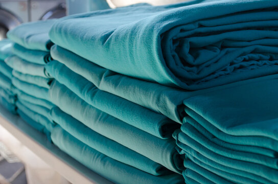 Stack of green folded surgical clothing in an industrial laundry.