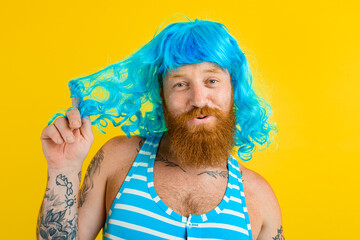 Happy man with life buoy, swimsuit and blue wig acts like a happy woman