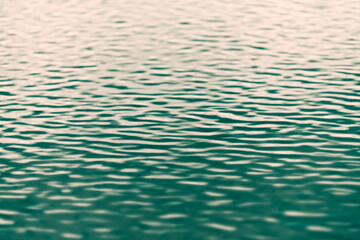 Light reflected on green water with ripples and shallow depth of field with blurred background and foreground