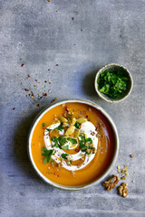 Delicious autumn pumpkin soup with cream and walnuts. Top view with copy space.