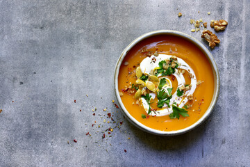 Delicious autumn pumpkin soup with cream and walnuts. Top view with copy space.
