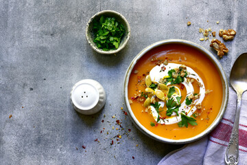 Delicious autumn pumpkin soup with cream and walnuts. Top view with copy space.