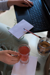 Woman with a tea cup on her hand and working on her laptop at home 