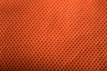 Texture of an orange reusable bag as background on a black table