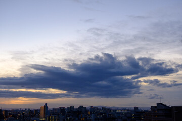 都市の夜明け、早朝ビルの隙間から太陽が昇り辺りはオレンジ色に染まる。ビルはシルエットに浮かぶ