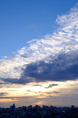 都会の夕暮れ。六甲山に沈む夕陽とオレンジ色に染まる雲と空。