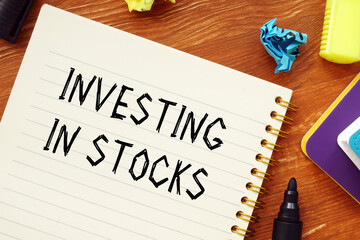 Naklejka premium Financial concept about INVESTING IN STOCKS question marks with phrase on the sheet.