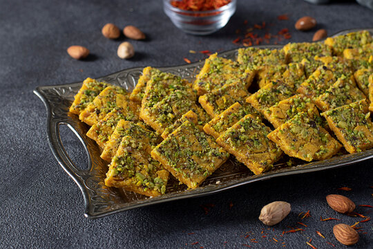 Traditional Persian dessert Sohan from Iran. Tea ceremony with sohan on dark gray background.