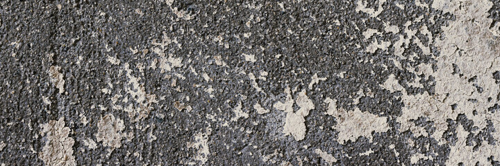 Peeling paint on the wall. Panorama of a concrete wall with old cracked flaking paint. Weathered rough painted surface with patterns of cracks and peeling. Wide panoramic grungy texture for background