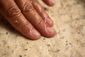Homemade pizza preparation process. Hands of a cook stretching the pizza dough still raw.