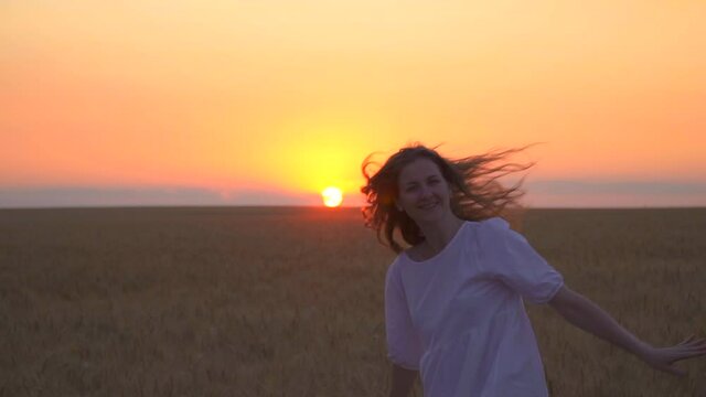 Beautiful caucasian woman is running in the field. The girl is dancing in nature. Mother nature. Have fun at sunset. The sun is golden on the horizon. Touch the wheat with your hands. Romantic dress.