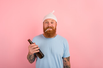 Happy man with beard and tattoos acts like a little newborn baby with beer in hand