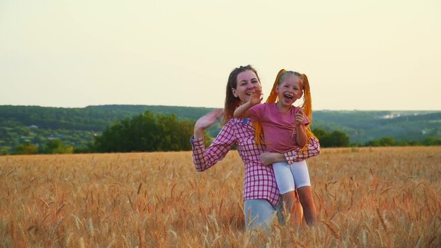 Mom and daughter have fun in the field. Family and nature in summer at sunset. Little girl and woman on vacation. Smile and be happy. Friendship of two daughters. Farmers are playing in the field.
