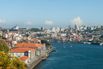 Obraz premium Landscape view of Porto, Gaia and river Douro on a sunny day with some yachts and boats passing by red-tiled roofs - Porto, Portugal