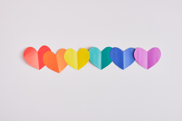 rainbow colored paper hearts on grey background, pride concept
