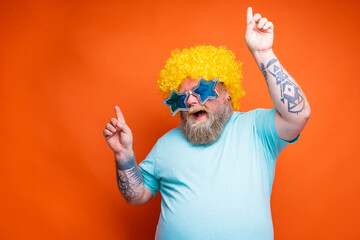 Fat happy man with beard, tattoos and sunglasses dances music on a disco
