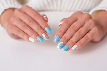 Beautiful female hands with romantic manicure nails, blue and white gel polish