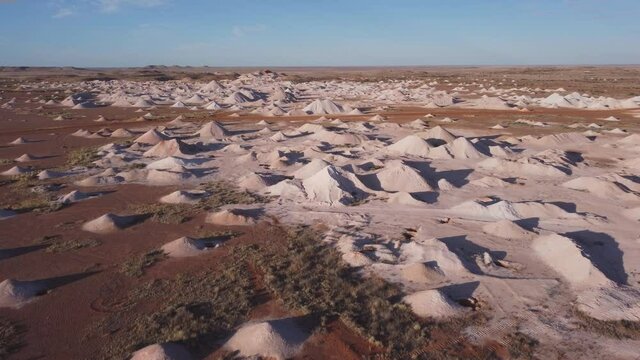 an aerial shot flying over opal mine tailings at coober pedy on a winter afternoon in outback south australia