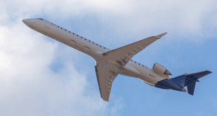 A commercial passenger plane flies in the sky. Bottom view.