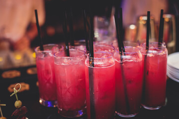 View of alcohol setting on catering banquet table, row line of red colored alcohol cocktails on a party, martini, vodka, spritz and others on decorated catering banquet table event