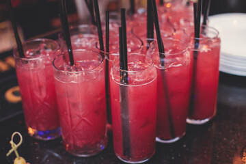 View of alcohol setting on catering banquet table, row line of red colored alcohol cocktails on a party, martini, vodka, spritz and others on decorated catering banquet table event