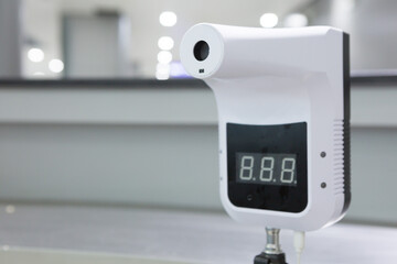 Infrared thermometer on blurred background. People must measure their temperature before entering the building or using any services.