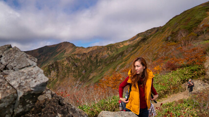Naklejka premium 秋の紅葉の季節 山登りをする女性