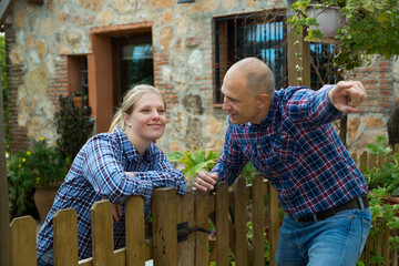 Man and woman communicate in a friendly way on the border of their farms. High quality photo