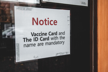 View of sign at the entrance of local restaurant BC Vaccine Card and ID Card with the name are mandatory