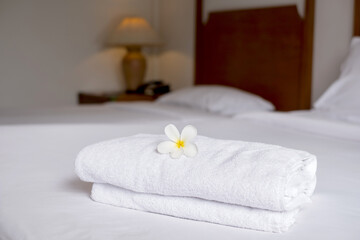 Fototapeta na wymiar A hotel maid stacked towels on the bed and placed flowers on the towels in a hotel room