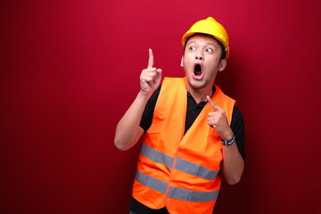 Shock Young asian man worker is surprised and shouting wow with pointing above with his hand...