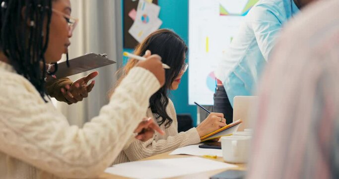 Passionate about their project. A group of young business people of different nationalities, working together in a creative office, sitting at a wooden desk on which there are mugs of coffee