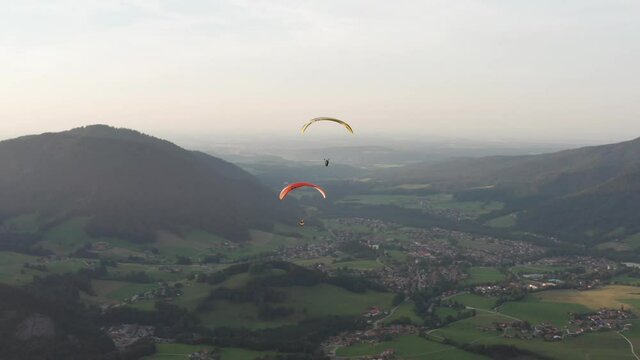 Aerial view people para gliding through sky, in Unternberg, Germany - pan drone shot