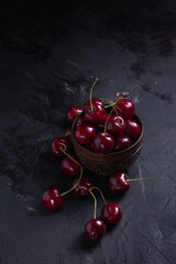 Organic juicy cherry in a bowl on dark background. Close-up photo, low key