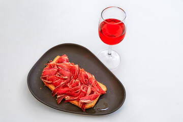 Glass of Spanish rose or rosado and Jamon Iberico tostada or ham and tomato sandwich at a...