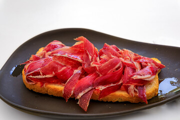 Serrano iberico ham sandwiches or bocadillo held on a wooden platter at a local shop in the old town or Casco Viejo of Pamplona, Spain