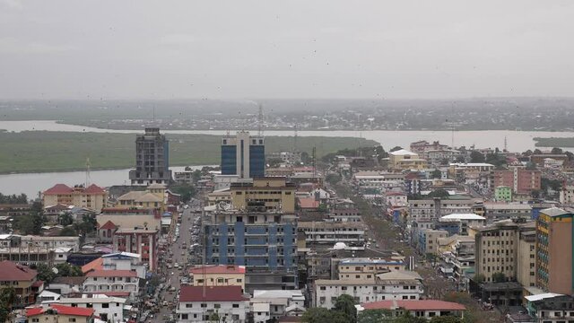 Still shot of skyline of Monrovia, Liberia on a cloudy day with bats flying overhead