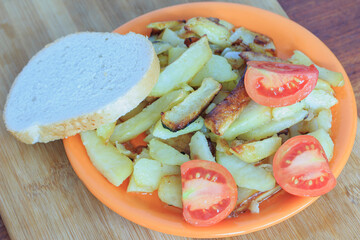 fried potatoes in a plate with a piece of bread and tomatoes top view