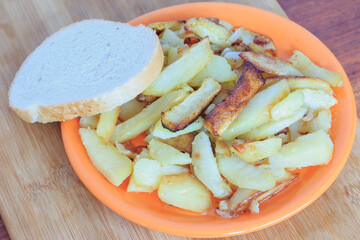  fried potatoes in a plate with a piece of bread on a wooden board