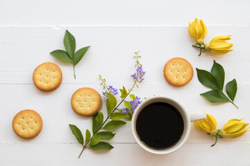 hot coffee espresso, biscuits dessert snack with yellow flowers ylang ylang arrangement flat lay style on background white