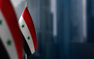 Small flags of Syria on a blurry background of the city