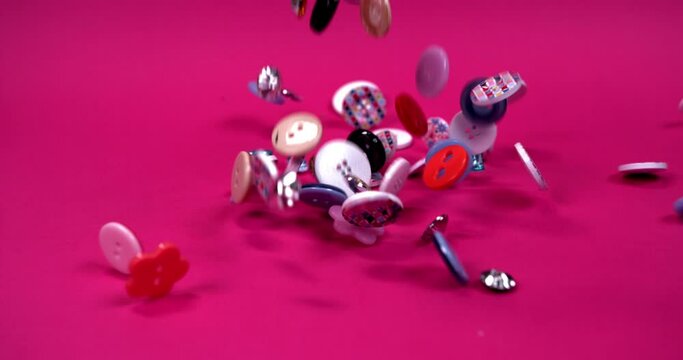 Multi-colored buttons of different shapes fall on a pink background