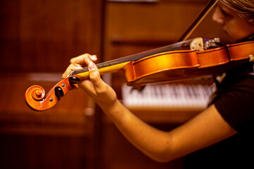 young violinist plays music on the violin with his back near the piano, horizontal