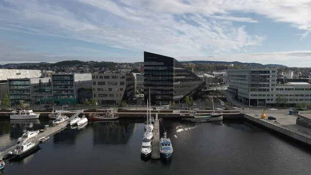 Boats, Offices, And Buildings Along Port Of Trondheim In Norway - aerial sideways