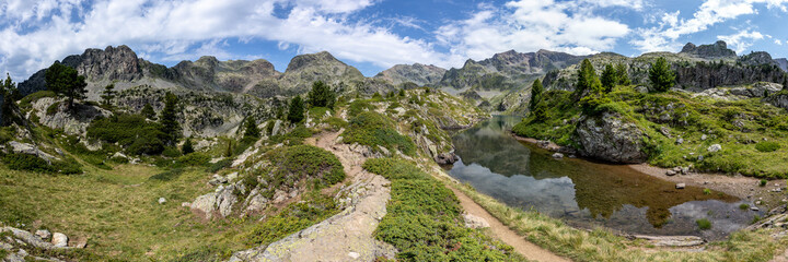 Photographie panoramique du lac longuet (Chamrousse, alpes) sous un ciel bleu parsemé de nuages blancs